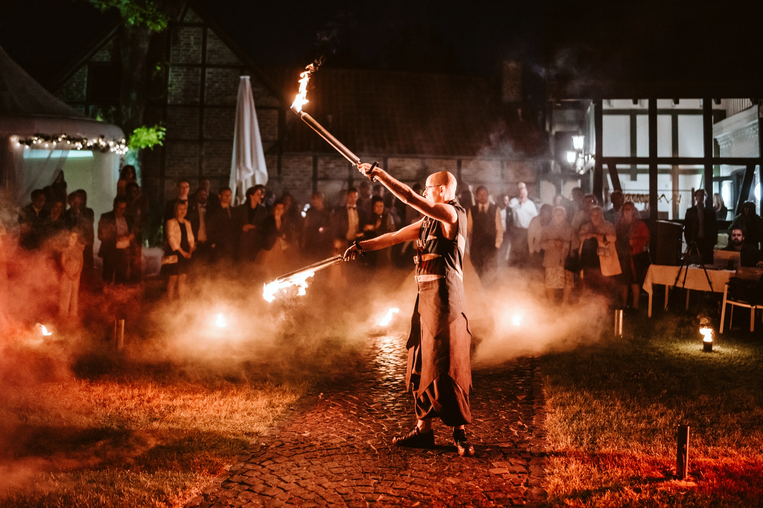 Feuerkünstler mit brennenden Requisiten vor Publikum